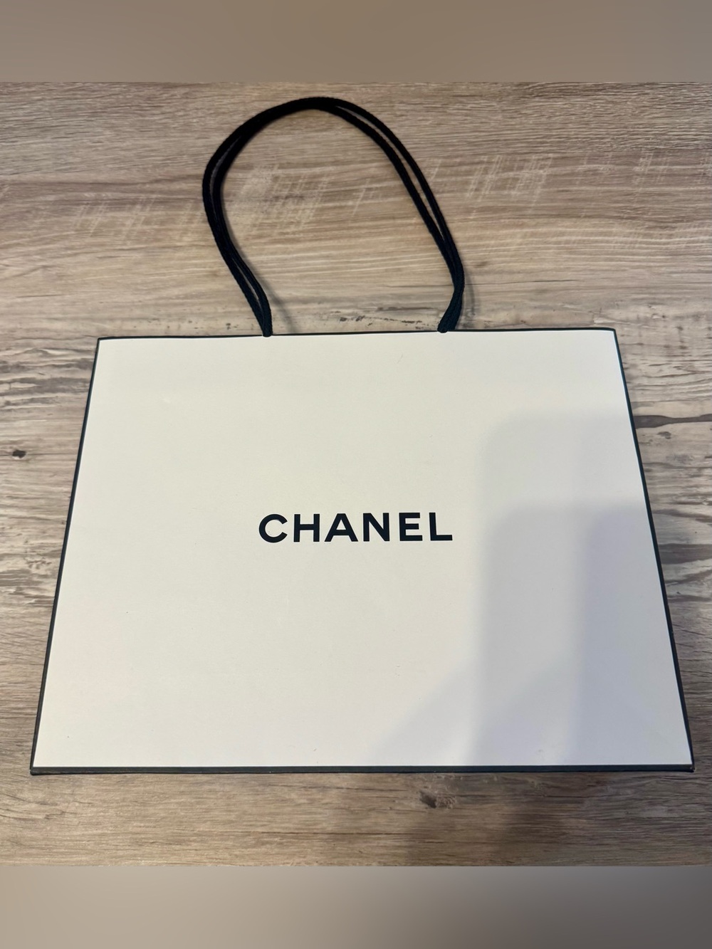 New white gift bag with black handles and lettering.